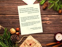 Ein weihnachtlich dekorierter Tisch mit Kerze, Tannengrün, Walnüssen, Haselnüssen und einem Briefumschlag. Daneben ein Brief mit dem Text: Im Grunde sind es immer die Verbindungen mit Menschen, die dem Leben seinen Wert geben. (Wilhelm von Humboldt).